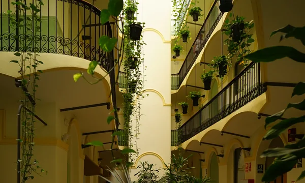 Patio central à cloître de l'Hotel Peninsular Barcelona (ex-couvent 1875), arcades jaune pâle, galeries en fer forgé et plantes grimpantes, Carrer de Sant Pau, Raval