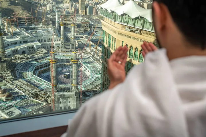 Un pèlerin prie devant la baie vitrée de sa chambre du Fairmont, avec la Kaaba en contrebas