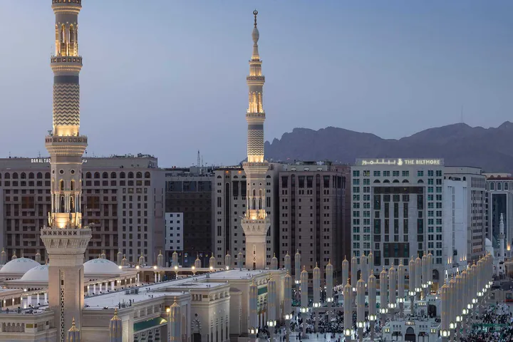 Les minarets du Masjid an-Nabawi au crépuscule ; l'enseigne The Biltmore est visible sur l'immeuble à droite