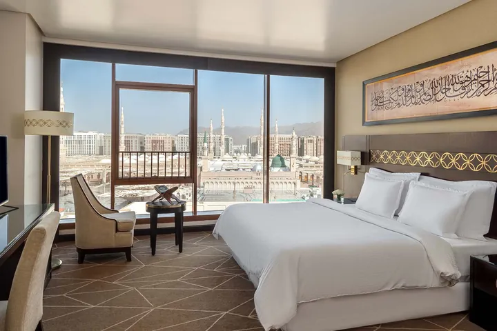 Chambre du Pullman Zamzam Madinah, baie vitrée donnant sur le dôme vert et les minarets du Masjid an-Nabawi