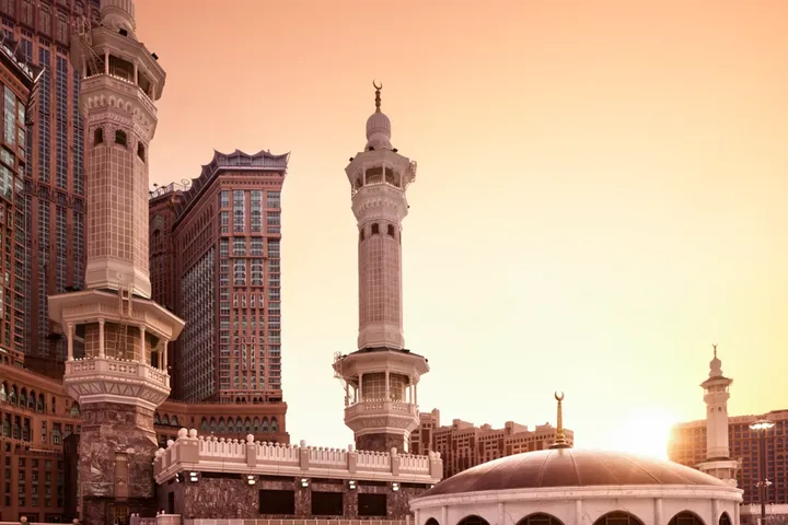 Les tours Abraj Al-Bait et un minaret de la Masjid al-Haram au coucher du soleil, vue officielle du Raffles Makkah Palace