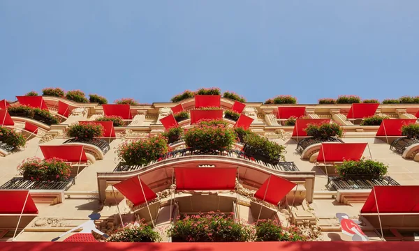 Façade de l'Hôtel Plaza Athénée, avenue Montaigne, avec ses stores rouges et ses jardinières fleuries